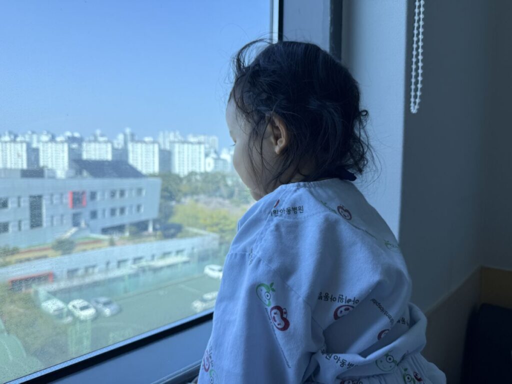 폐렴 진단 후 병원 환자복을 입고 창밖을 바라보고 있는 딸아이의 뒷모습 사진